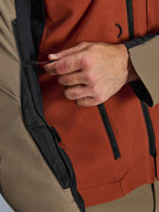 Alpinestars AMT-8 Stretch Drystar® XF Jacket, Walnut Rust Black, zbliżenie na system wentylacji klatki piersiowej, dłoń regulująca ściągacz sznurkowy, techniczny materiał z czarnymi zamkami, ujęcie detalu motocyklowej kurtki adventure