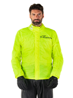 Alpinestars Hurricane Rain V2 Jacket, motocyklowa kurtka przeciwdeszczowa, kolor żółty fluo, noszona przez modela z czarnymi spodniami i rękawicami, wysoki kołnierz z elementami odblaskowymi, przednia listwa ochronna z logo Alpinestars, wodoodporna odzież o wysokiej widoczności