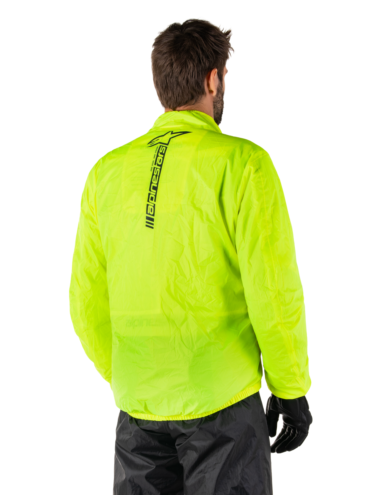 Kurtka przeciwdeszczowa Alpinestars Hurricane Rain V2, żółty fluo, widok z tyłu na modelu, pionowy czarny napis Alpinestars na środku pleców, elastyczny pas i mankiety, wodoodporna i kompaktowa konstrukcja