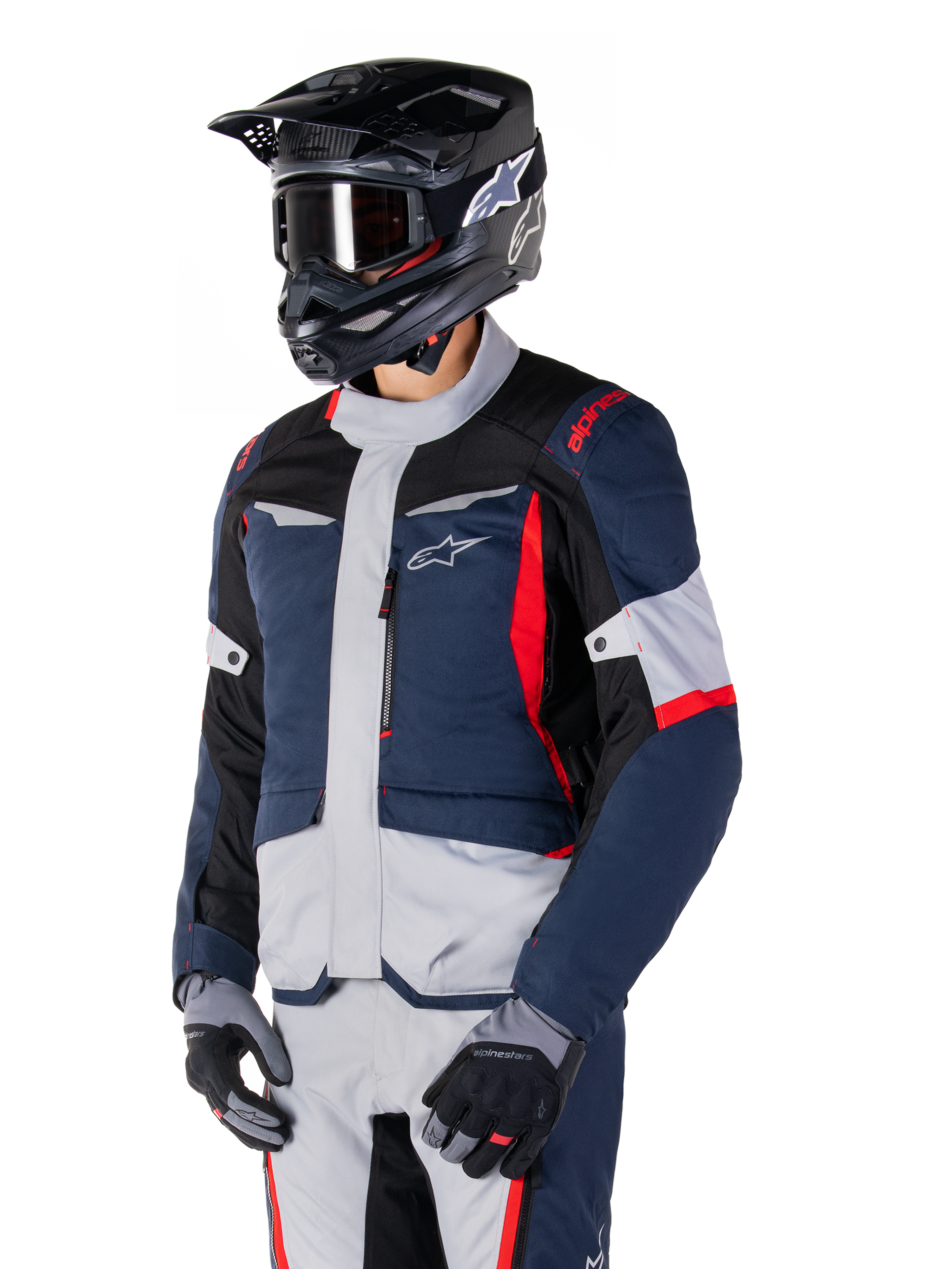 Alpinestars ST-1 Waterproof Jacket, adventure touring motorcycle jacket in Dark Blue, Black, and Bright Red, worn with a black helmet and grey gloves, featuring a modern design with functional pockets and Alpinestars branding.