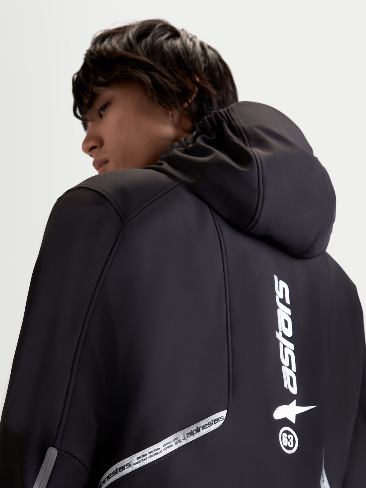 Alpinestars C-5 Drystar kurtka motocyklowa miejska męska, czarna, widok z tyłu na model prezentujący zintegrowany kaptur i odblaskowe detale z brandingiem
