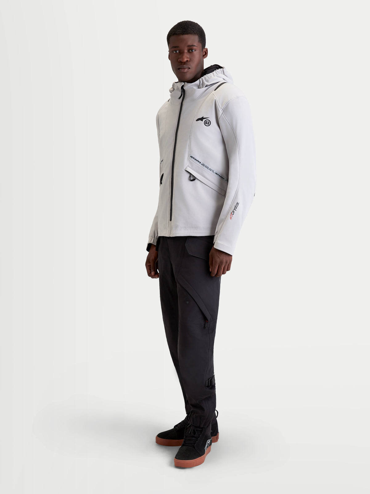 Alpinestars C 5 Drystar kurtka motocyklowa miejska męska w kolorze jasnoszarym i czarnym, na modelu prezentującym wodoodporną konstrukcję softshell, zintegrowany kaptur oraz elementy ochronne