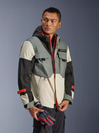 Alpinestars Mospher Waterproof Jacket w kolorze Fur Gray Black Ice, wielopanelowa tekstylna parka z szarymi, czarnymi i kremowymi sekcjami, z jaskrawoczerwonymi akcentami na suwakach i paskach, taktyczny design z kapturem i kieszeniami użytkowymi, noszona przez modela trzymającego rękawice motocyklowe.