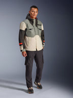 Kurtka wodoodporna Alpinestars Mospher w kolorze Fur Gray Black Ice, wielokolorowa techniczna parka motocyklowa z szarymi, czarnymi i kremowymi panelami oraz czerwonymi akcentami, funkcjonalny design z dużymi kieszeniami i kapturem, noszona z ciemnoszarymi spodniami cargo i czarnymi sneakersami, nowoczesna miejska odzież motocyklowa