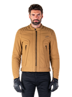 Alpinestars Clayton WR Jacket, Urban Motorcycle Jacket, Utility Brown Light Gold, water-resistant textile with quilted padded shoulders, high biker collar, black zipper details, and chest logo, worn with black protective gloves and pants