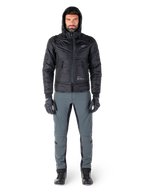Kurtka Alpinestars Mohobbs Waterproof w kolorze czarnym, męski model w pikowanej kurtce typu bomber z kapturem, zestawiona z szarymi spodniami motocyklowymi, czarnymi rękawicami i butami, miejska współczesna odzież motocyklowa