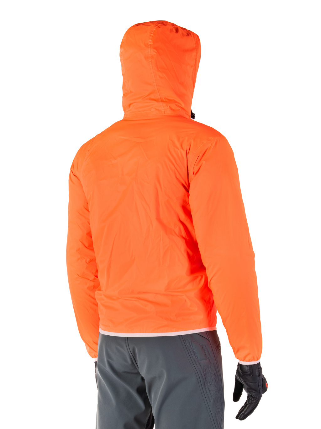 Alpinestars Mohobbs Waterproof Jacket, pakowalna awaryjna osłona przeciwdeszczowa w kolorze jaskrawym Orange Fluo, widok z tyłu prezentujący kaptur sztormowy, noszona z ciemnoszarymi spodniami motocyklowymi i czarnymi rękawicami, lekka wodoodporna miejska odzież motocyklowa