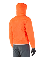 Alpinestars Mohobbs Waterproof Jacket, pakowalna awaryjna osłona przeciwdeszczowa w kolorze jaskrawym Orange Fluo, widok z tyłu prezentujący kaptur sztormowy, noszona z ciemnoszarymi spodniami motocyklowymi i czarnymi rękawicami, lekka wodoodporna miejska odzież motocyklowa