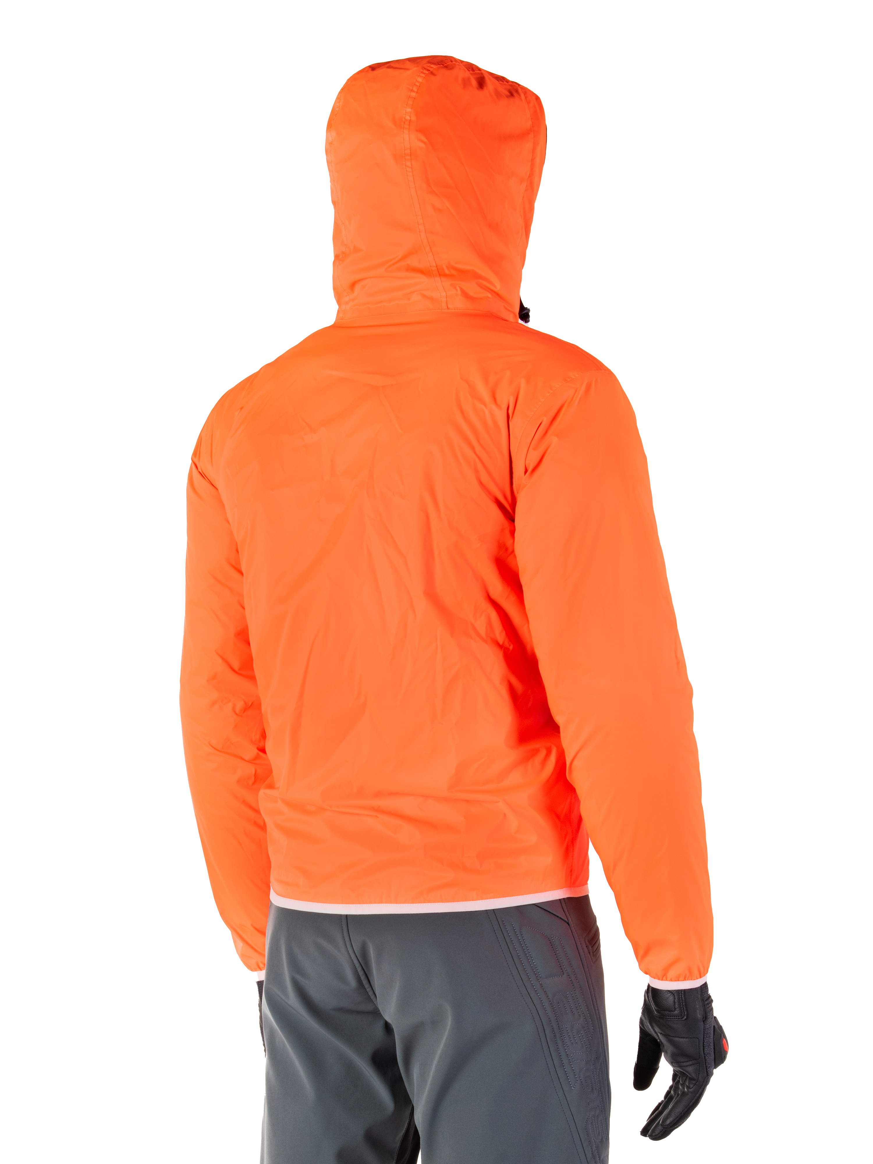 Alpinestars Mohobbs Waterproof Jacket, pakowalna awaryjna osłona przeciwdeszczowa w kolorze jaskrawym Orange Fluo, widok z tyłu prezentujący kaptur sztormowy, noszona z ciemnoszarymi spodniami motocyklowymi i czarnymi rękawicami, lekka wodoodporna miejska odzież motocyklowa