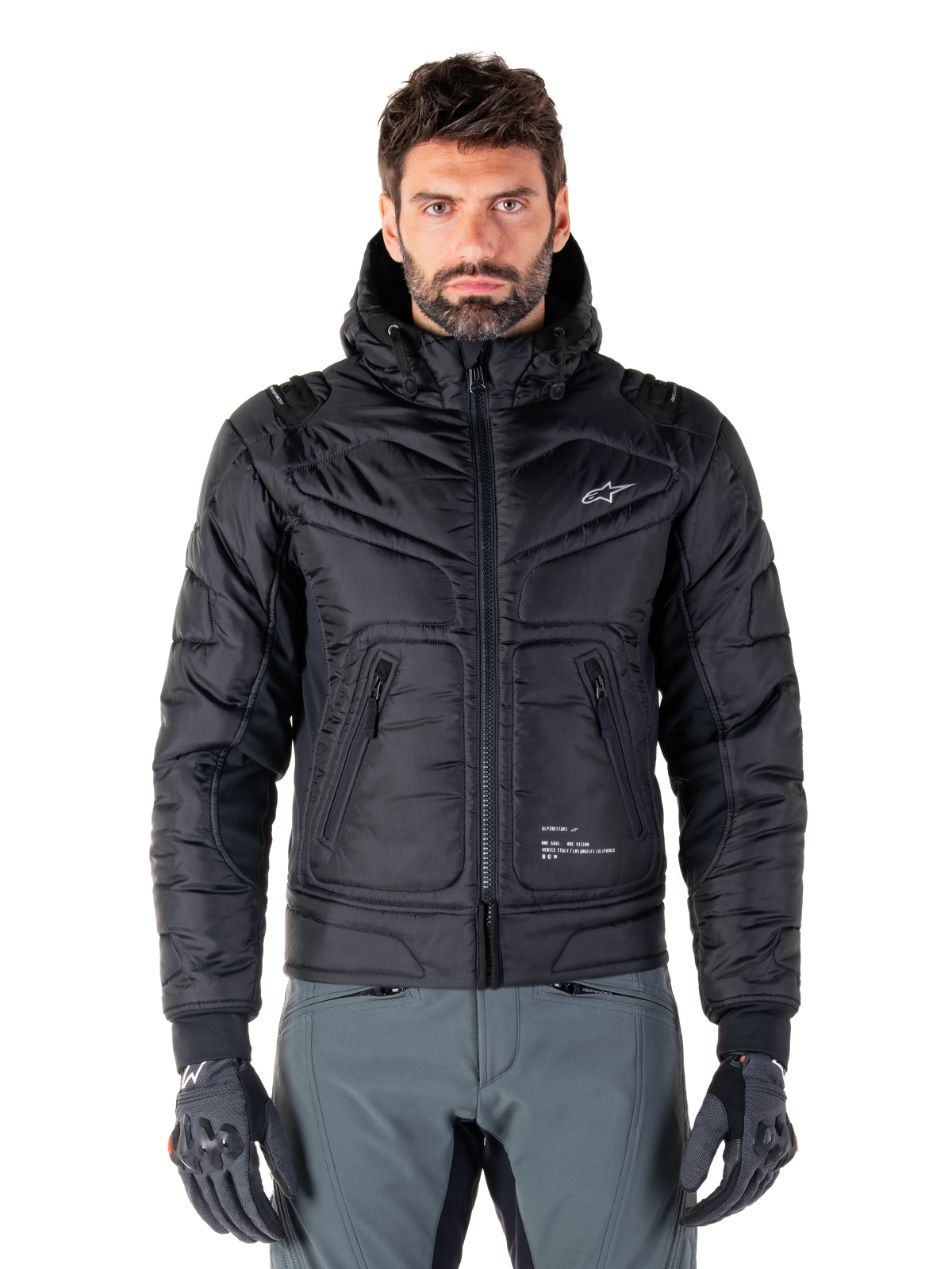 Alpinestars Mohobbs Waterproof Jacket, Black Padded Bomber Motorcycle Jacket, quilted poly fabric with front zipper and zippered pockets, small white logo on chest, worn by a model with grey pants and gloves, urban streetwear design for city riding.