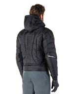 Alpinestars Mohobbs Waterproof Jacket, czarna, widok z tyłu prezentujący pikowaną, wyściełaną konstrukcję, kaptur, pionowy napis „astars” na plecach oraz branding Alpinestars na rękawach, noszona z szarymi spodniami i czarnymi rękawicami.
