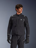 Alpinestars Andes Pro Drystar® XF Jacket, black and dark gray motorcycle adventure touring jacket, worn with matching pants and gloves, featuring technical laminated shell construction, ALL TERRA chest logo, reflective details, and adjustable cuffs