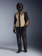 Kurtka Alpinestars Andes Pro Drystar® XF w kolorze Walnut Aluminum, motocyklowa kurtka adventure noszona z pasującymi czarnymi spodniami, czarnym kaskiem adventure z goglami i czarnymi butami, z beżowymi i czarnymi panelami oraz czerwonymi akcentami.