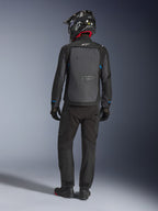 Kurtka Alpinestars Cusco Drystar®, czarna i ciemnoszara, widok z tyłu motocyklisty w pełnym stroju adventure touring, duży szary panel na plecach z logo Alpinestars, niebieskie akcenty na rękawach, noszona z pasującymi czarnymi spodniami i kaskiem.