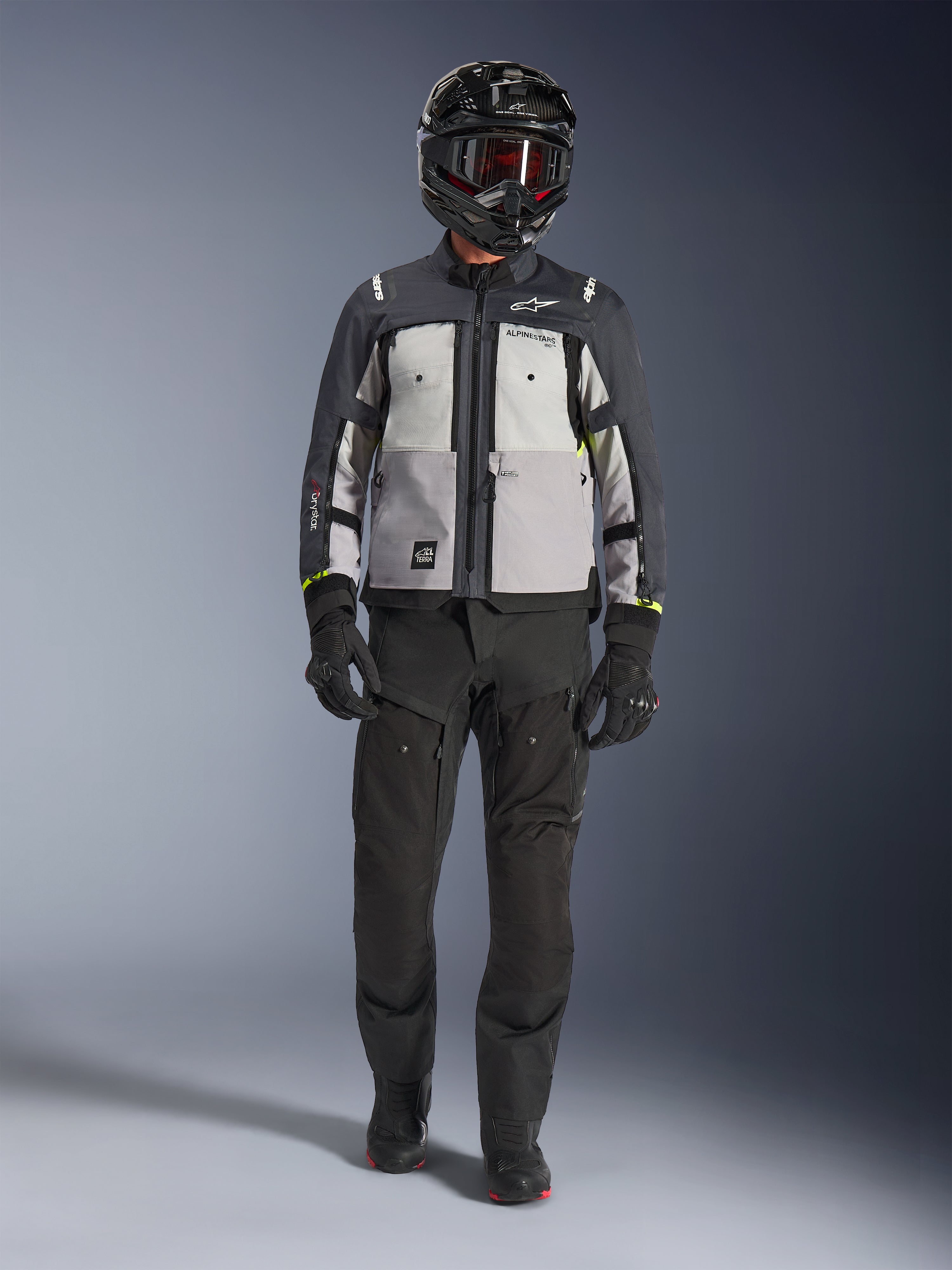 Alpinestars Cusco Drystar® Jacket, Ice Gray Mid Gray Deep Gray, adventure motorcycle jacket worn with black riding pants, black gloves, and a black helmet with goggles, featuring color-blocked gray panels and technical detailing for road and adventure touring.