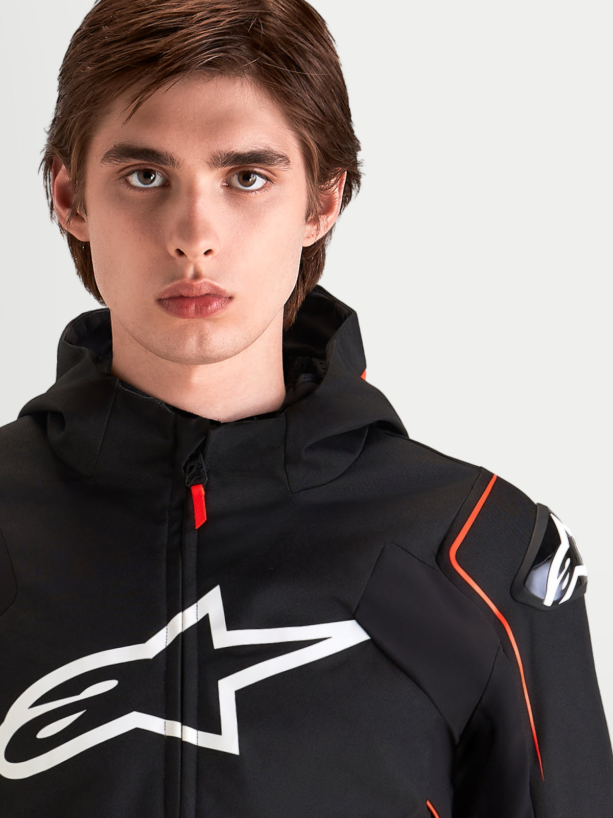 Alpinestars Zaca V 2 Waterproof, męska wodoodporna kurtka motocyklowa sportowa, czarna z czerwonymi akcentami, ochrona ramion DFS i duże logo na klatce piersiowej, portret zbliżeniowy motocyklisty