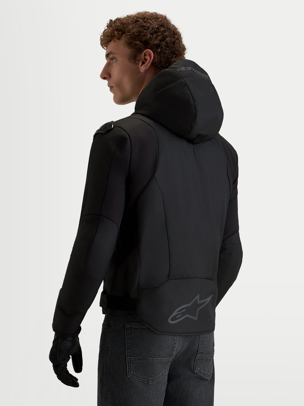 Alpinestars Zaca V2 Waterproof Kurtka, męska czarna kurtka motocyklowa ze zintegrowanym kapturem, przedłużonym tyłem z logo Alpinestars oraz konstrukcją kompatybilną z Tech-Air, widok z tyłu na modelu