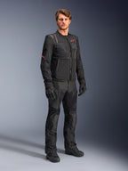 Męski model w czarnej kurtce Alpinestars ST-2 Air, z czerwonym logo gwiazdy i brandingiem „Alpinestars Exploration Equipment”, w zestawieniu z czarnymi spodniami motocyklowymi, rękawicami i butami, nowoczesny letni strój turystyczny.