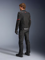 Alpinestars ST-2 Air Jacket, czarna kurtka motocyklowa, widok z tyłu na modelu z czerwonym logo gwiazdy w górnej części pleców i odblaskowym brandingiem Alpinestars w pasie, w zestawieniu z pasującymi czarnymi technicznymi spodniami i rękawicami.