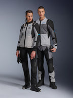 Mężczyzna i kobieta w kurtkach Alpinestars Stella ST-2 Air i pasujących spodniach technicznych, kolorystyka Ice Gray i Black z niebieskimi akcentami, panele wentylacyjne z siatki, branding „ALPINESTARS EXPLORATION EQUIPMENT”, studyjne ujęcie pary