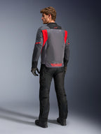 Mężczyzna widoczny od tyłu w kurtce Alpinestars St-2 Air w kolorach Deep Gray, Dark Gray i Bright Red, prezentujący duży siatkowy panel wentylacyjny na plecach i czerwone oznaczenia marki, zestawiony z czarnymi spodniami motocyklowymi i szarymi rękawicami.