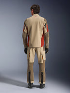 Widok z tyłu motocyklisty ubranego w kurtkę Alpinestars Maxdura Drystar®XF Laminated Armored Shell i dopasowane spodnie adventure w kolorze Aluminum Walnut Rust Brown, piaskowa i brązowa tkanina z pomarańczowymi akcentami, czarne buty i rękawice motocyklowe, profesjonalny zestaw odzieży adventure touring.