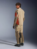 Model w kurtce Alpinestars Maxdura Drystar®XF Laminated Armored Shell w kolorze Aluminum Walnut Rust Brown, pasujących spodniach turystycznych adventure, czarnych rękawicach i czarnych butach, widok z tyłu prezentujący techniczną konstrukcję tekstylną oraz wzmocnione strefy.