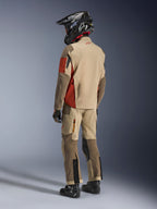 Motocyklista adventure widoczny z tyłu, ubrany w kurtkę Alpinestars Maxdura Drystar®XF Laminated Armored Shell w kolorze Aluminum Walnut Rust Brown, w zestawie z pasującymi spodniami motocyklowymi, czarnym kaskiem off-road i czarnymi butami; kompletny techniczny strój turystyczny.