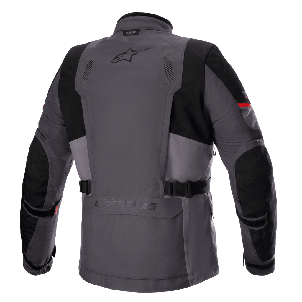 Kurtka Alpinestars Monteira Drystar® XF, turystyczna kurtka motocyklowa adventure, ciemnoszara i grafitowa (Tar Gray) z jaskrawoczerwonymi akcentami, widok z tyłu pokazujący tylną kieszeń, paski w talii oraz wzmocnione czarne panele na barkach i łokciach, logo Astars w górnej części pleców