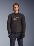 Alpinestars SMX Waterproof Jacket, czarna tekstylna kurtka motocyklowa z biało-czerwonym logo gwiazdy na piersi, noszona przez modela w czarnych rękawicach i niebieskich jeansach, wyposażona w zewnętrzne slidery na ramionach i sportowy krój.