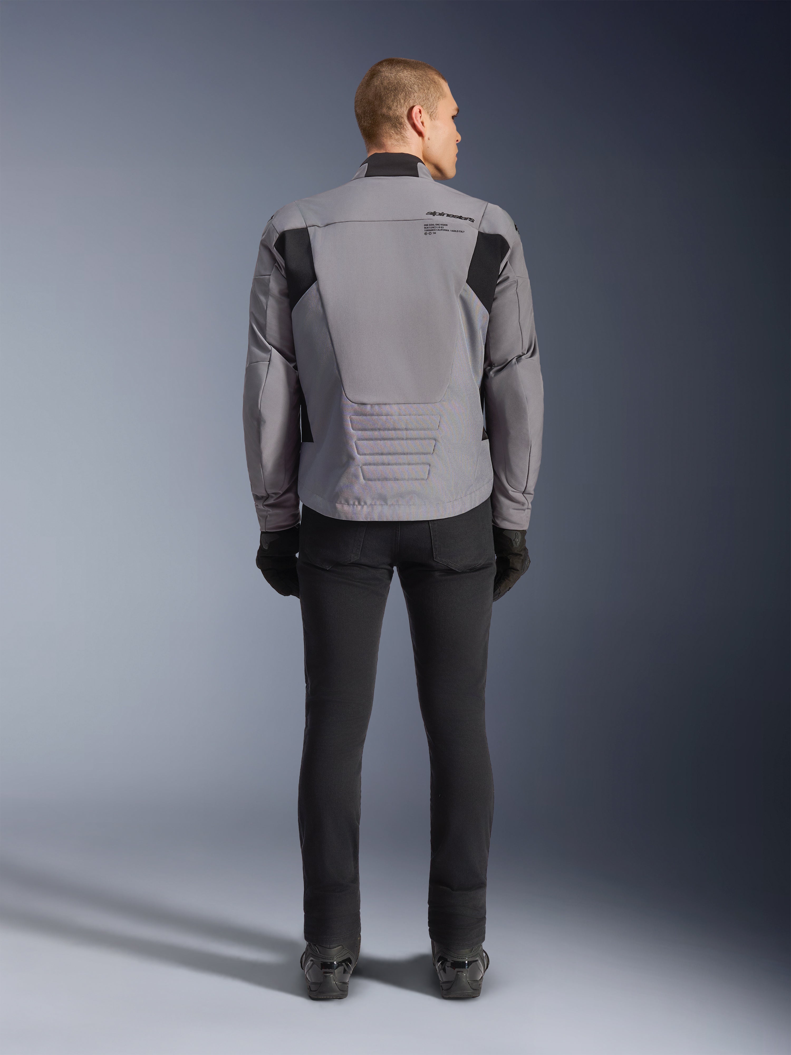 Alpinestars SMX Waterproof Jacket, widok z tyłu, kolor ciemnoszary i czarny, z czarnymi panelami tekstylnymi na ramionach i sportowym krojem, w zestawieniu z czarnymi spodniami i rękawicami dla kompletnego motocyklowego wyglądu