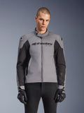 Alpinestars SMX Waterproof Jacket, sportowa drogowa kurtka motocyklowa, ciemnoszara i czarna, z wysokim kołnierzem i slajderami ramion DFS Lite, noszona z czarnymi rękawicami SMX, dopasowany sportowy krój do jazdy w każdych warunkach pogodowych