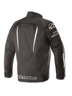 Alpinestars Gunner V2 Waterproof Jacket, wodoodporna kurtka motocyklowa, widok z tyłu, czarno-biała, tekstylna konstrukcja z pionowymi białymi akcentami, duże logo Alpinestars na dole pleców i logo A-star na ramieniu, miejska odzież motocyklowa