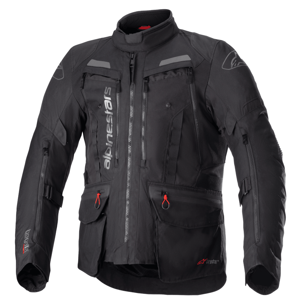Alpinestars Bogota Pro Drystar Jacket, czarna turystyczna kurtka motocyklowa, szare i czerwone akcenty, duże panele wentylacyjne na klatce piersiowej, wodoodporne kieszenie z czerwonymi uchwytami zamków, wysoki kołnierz ochronny, trwała tekstylna konstrukcja do jazdy typu adventure