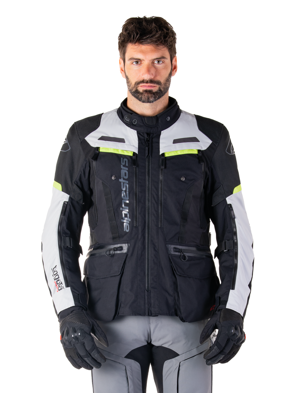 Man wearing Alpinestars Bogotá Pro Drystar® Jacket, Black Ice Gray and Yellow Fluo, all-season adventure touring motorcycle jacket, waterproof design with multiple pockets and vertical branding, paired with black gloves and gray riding pants