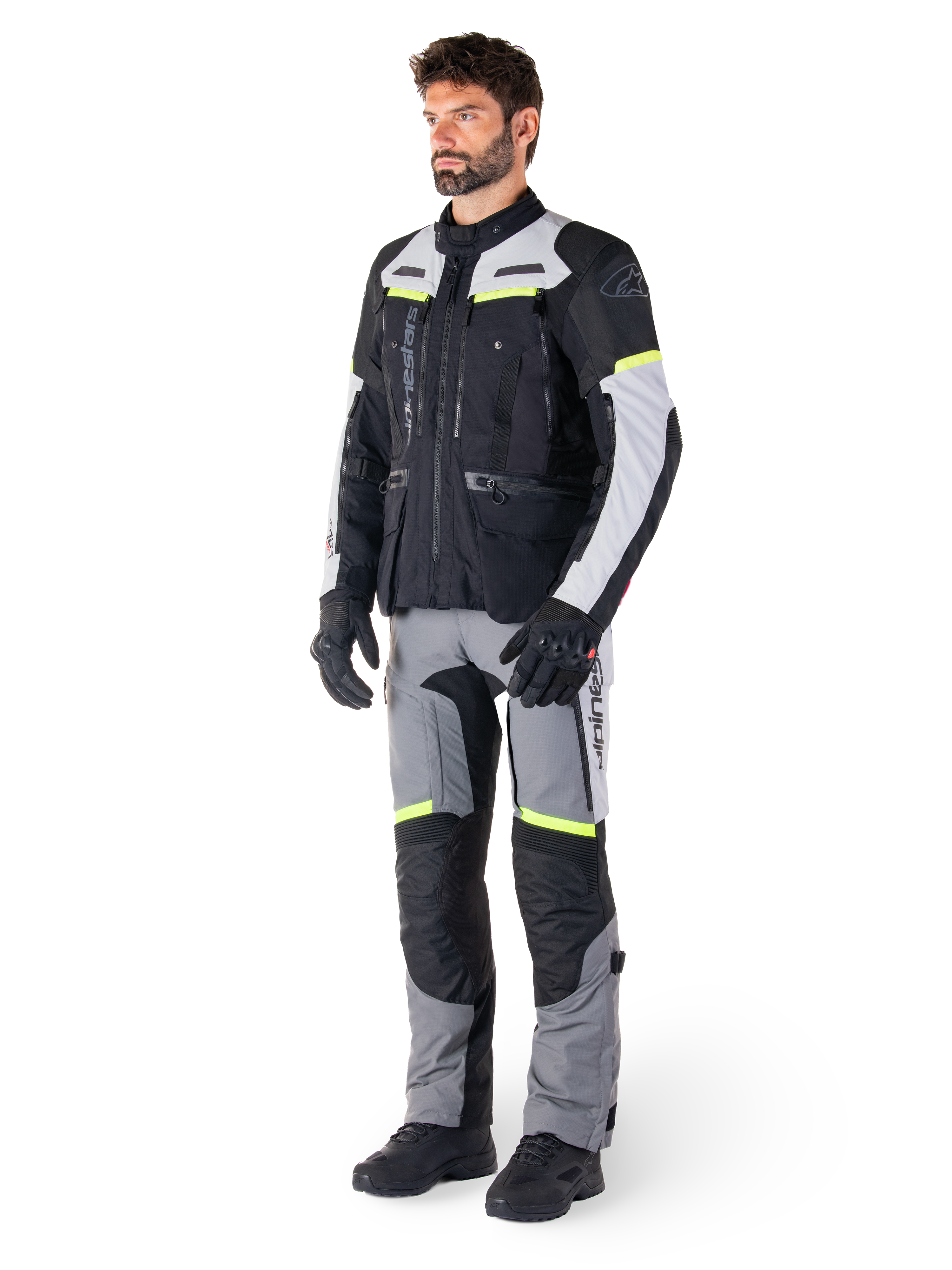 Alpinestars Bogotá Pro Drystar® Jacket, adventure touring motorcycle jacket, Black Ice Gray Yellow Fluo, worn by model with matching pants and black gloves, featuring waterproof textile construction with ventilation panels and fluorescent accents.