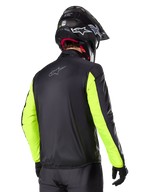 Alpinestars Bogotá Pro Drystar® Jacket, Rear view, Black with Yellow Fluo sleeves, worn by a rider with a black helmet and gloves, high-visibility adventure touring motorcycle gear with a technical textile finish.