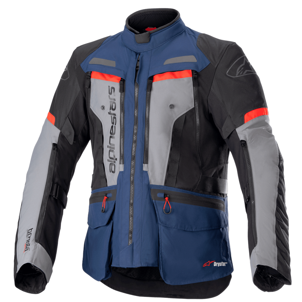 Alpinestars Bogota Pro Drystar Jacket, motocyklowa kurtka turystyczna adventure, ciemnoniebieska i czarna z szarymi panelami na klatce piersiowej i jaskrawoczerwonymi akcentami, wodoodporna konstrukcja tekstylna, liczne zamki wentylacyjne i kieszenie użytkowe.
