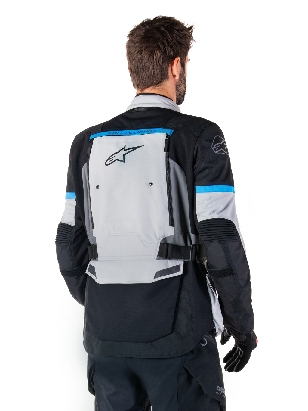 Kurtka Alpinestars Bogota' Pro Drystar®, kurtka motocyklowa adventure, szaro-czarno-błękitna, widok z tyłu prezentujący duży szary panel z logo Tech Touring, błękitne akcenty na rękawach, wytrzymała konstrukcja tekstylna