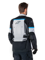 Kurtka Alpinestars Bogota' Pro Drystar®, kurtka motocyklowa adventure, szaro-czarno-błękitna, widok z tyłu prezentujący duży szary panel z logo Tech Touring, błękitne akcenty na rękawach, wytrzymała konstrukcja tekstylna