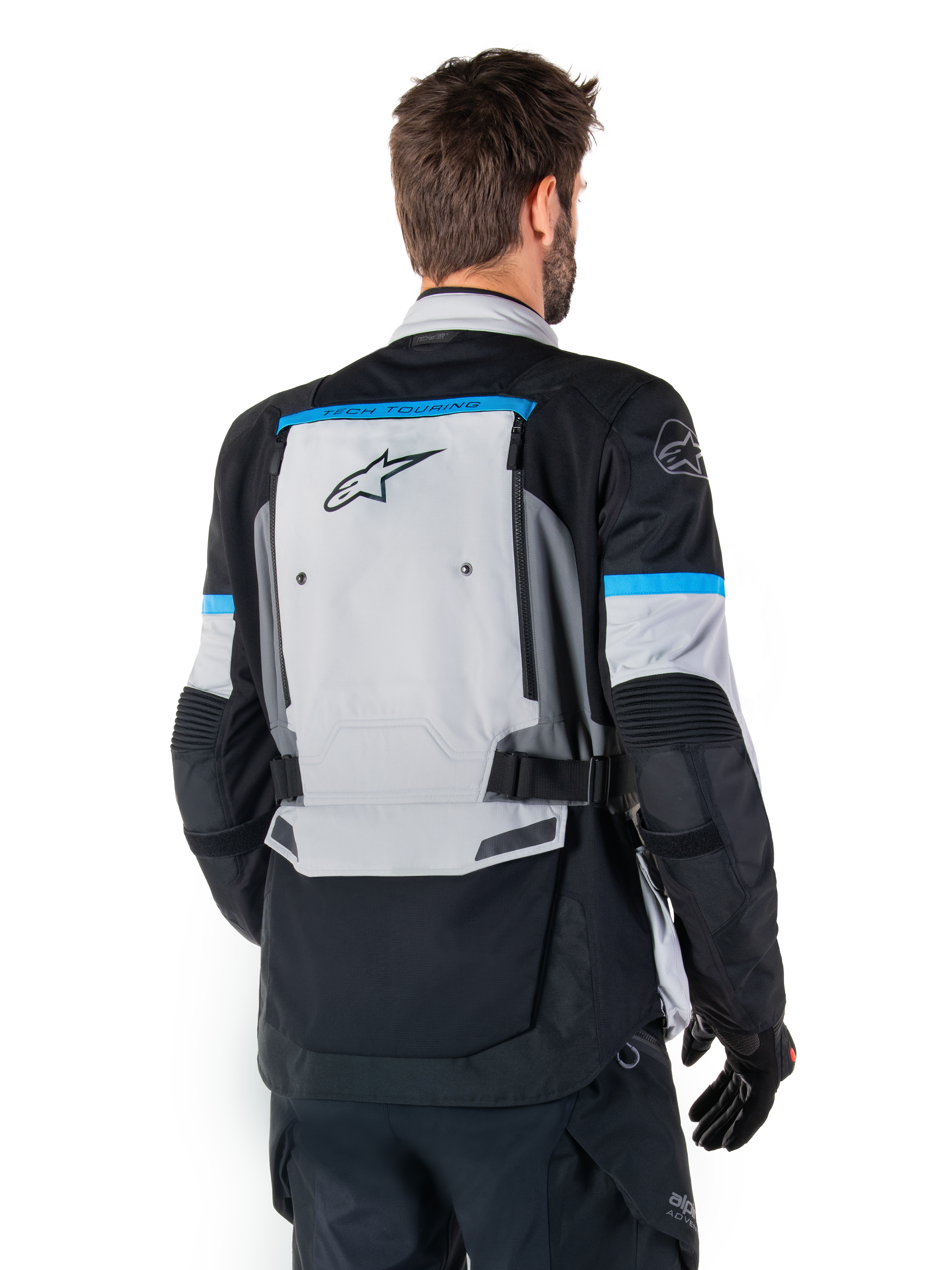 Kurtka Alpinestars Bogota' Pro Drystar®, kurtka motocyklowa adventure, szaro-czarno-błękitna, widok z tyłu prezentujący duży szary panel z logo Tech Touring, błękitne akcenty na rękawach, wytrzymała konstrukcja tekstylna
