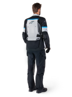 Kurtka Alpinestars Bogotá Pro Drystar®, motocyklowa kurtka adventure, kolor lodowy szary, czarny i cyjan, widok z tyłu z pasującymi czarnymi spodniami i rękawicami, duży szary panel na plecach z czarnym logo Alpinestars i błękitnymi akcentami.