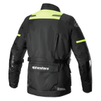 Kurtka Alpinestars Andes V3 Drystar®, widok z tyłu przygodowej kurtki motocyklowej w kolorze czarnym i żółtym fluo, z dużą kieszenią użytkową na dole pleców z logo Alpinestars, panelami o wysokiej widoczności na ramionach i regulowanymi paskami w talii.