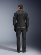 Widok z tyłu motocyklisty ubranego w kurtkę Alpinestars Andes Air Drystar® w kolorze czarnym, z rozległymi panelami wentylacyjnymi z siatki na plecach, czerwonym logo Alpinestars i odblaskowymi akcentami, w zestawie z pasującymi spodniami motocyklowymi i rękawicami do turystyki adventure.