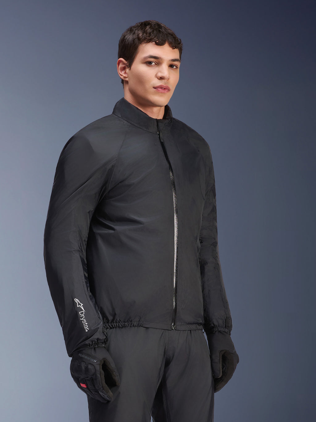 Alpinestars Andes Air Drystar® Jacket, wodoodporna membrana, czarna, prezentowana przez modela w czarnych rękawicach i spodniach, lekka tkanina techniczna z logo „Drystar” na rękawie, zdjęcie studyjne