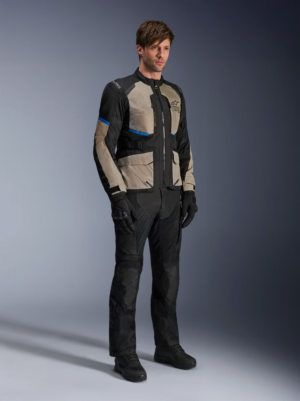 Kurtka Alpinestars Andes Air Drystar®, motocyklowa kurtka turystyczna, czarna z szarymi i jasnoniebieskimi akcentami, noszona z pasującymi spodniami i rękawicami, obszerne panele z siatki dla przepływu powietrza, krój szosowy, odzież adventure touring