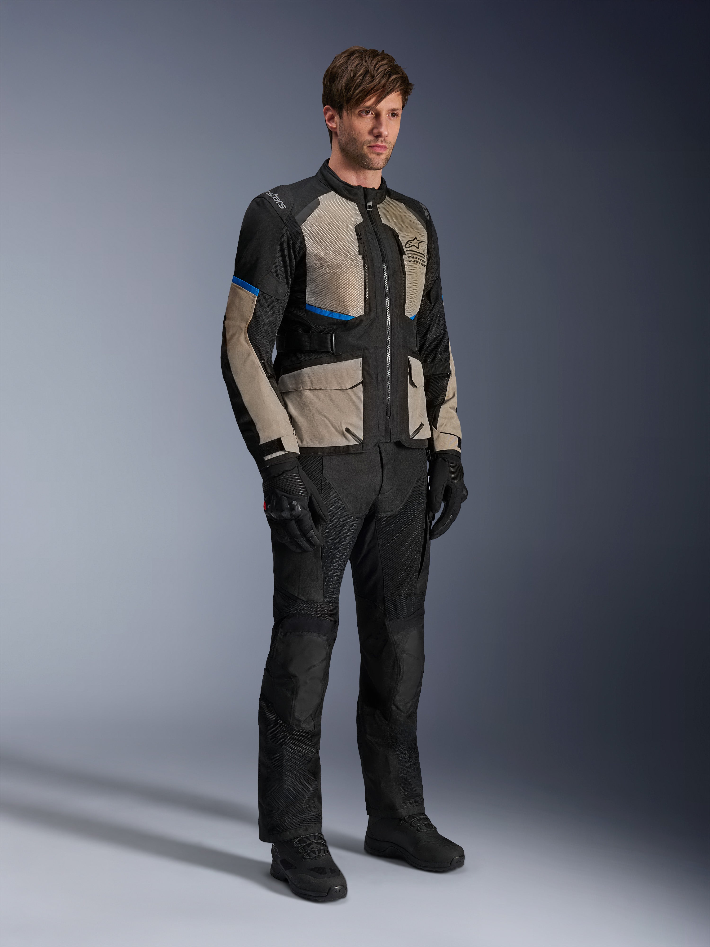 Kurtka Alpinestars Andes Air Drystar®, motocyklowa kurtka turystyczna, czarna z szarymi i jasnoniebieskimi akcentami, noszona z pasującymi spodniami i rękawicami, obszerne panele z siatki dla przepływu powietrza, krój szosowy, odzież adventure touring