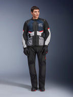 Kurtka Alpinestars Andes Air Drystar®, motocyklowa kurtka turystyczna, ciemnoniebieska, czarna i jasnoszara, noszona z pasującymi czarnymi spodniami adventure i rękawicami, panele z siatki dla przepływu powietrza, techniczna konstrukcja z wieloma kieszeniami.