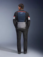 Kurtka Alpinestars Andes Air Drystar, Deep Blue Black Ice Gray, widok z tyłu na modelu, niebieski siatkowy panel wentylacyjny na plecach, duża szara kieszeń u dołu, czerwone i białe akcenty na rękawach, napis „alpinestars”, zestawiona z czarnymi spodniami motocyklowymi dla pełnego zestawu turystycznego