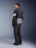 Męski model w ujęciu z tyłu i z boku, ubrany w kurtkę Alpinestars Andes Air Drystar® w kolorze Deep Blue Black Ice Gray, czarne spodnie motocyklowe i rękawice, niebieski panel siatkowy na plecach, szara kieszeń cargo na dole pleców i czerwone akcenty na rękawach, profesjonalna odzież adventure touring.